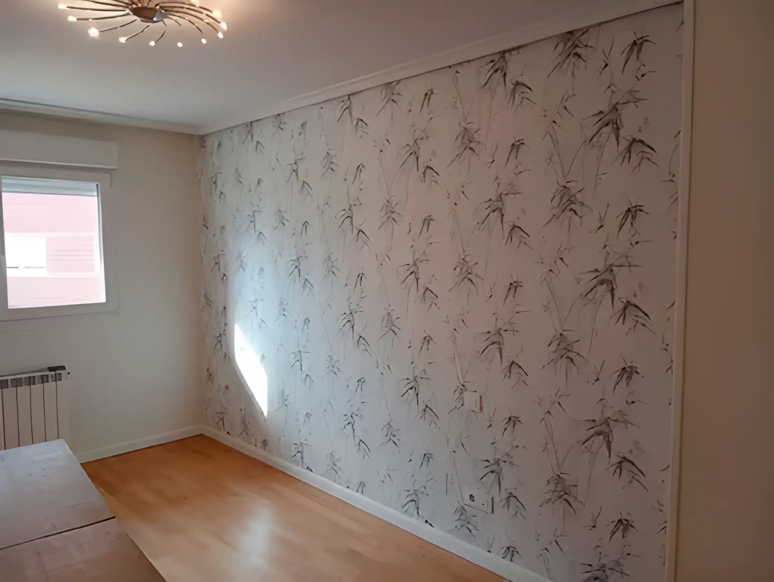Los Pintores Albacete colocando papel pintado en pared de acento de habitación luminosa